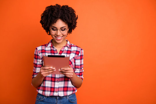 Portrait of nice cute attractive cheerful cheery smart clever intellectual wavy-haired lady nerd wearing checked shirt reading digital e-book isolated over bright vivid shine orange background