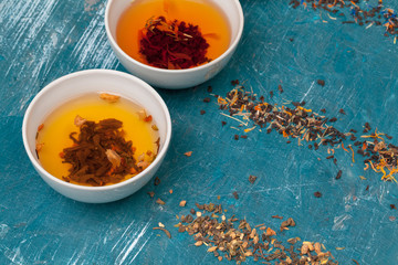 Tea concept. Different kinds of dry tea in ceramic bowls and cups of aromatic tea