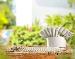 Desk of free space and grill time and cook hat. Summer garden background.