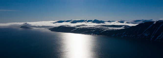 The mountainous sea coast covered with snow in a sunny weather. © Valerii