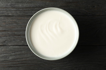 Bowl of sour cream yogurt on dark wooden background