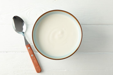 Bowl of sour cream yogurt with spoon on white background