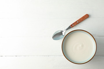 Bowl of sour cream yogurt with spoon on white background