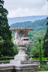 Classic stone sculpture  vase in a large park on the mountain background