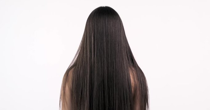Woman moves long hair. Rear view. Girl shakes long straight hair. Slow motion footage. Rear view. 4k. Female model is fluttering hair.