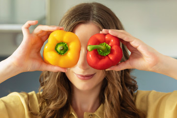 A young beautiful girl holds a sweet pepper in her hands, have fun and closes their eyes. A woman prepares a salad of fresh, healthy vegetables.