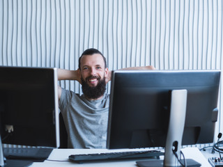 Successful professional career. Cheerful male web designer sitting at his workplace, smiling. Copy...