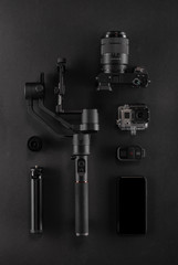 Work space videographer with laptop, digital camera, memory card, action camera, drone, remote controller, phone and camera accessory. Top view on black table background. Concept of mockup template.