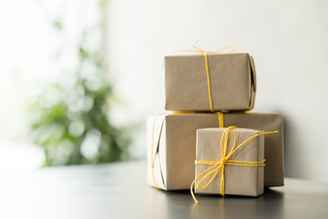 Corporate party celebration. Closeup of beige paper wrapped gift boxes stack over blur office...