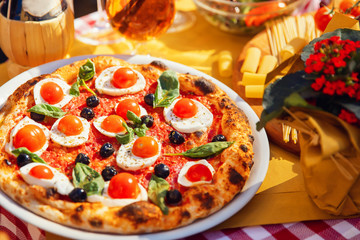 Italian pizza with tomatoes, mozzarella cheese, basil, black olives on board. Concept restaurant