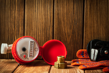 New water meter with fittings and wrench on a vintage wooden background.