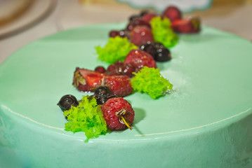 Round cake with green stuffed in a storefront. Berries on a cake.