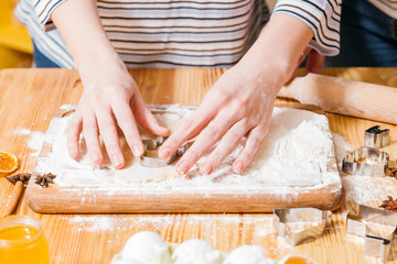 Obraz na płótnie Canvas Homemade cookies recipe. Closeup of woman hands cutting dough, making gingerbread biscuits.