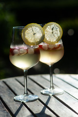 Refreshing fruit drinks with strawberries, ice and slice of lemon on wooden garden table