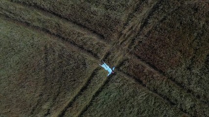 Young lady between 30 and 35 years old lying in the field. Aerial shooting