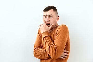 Fear,Shame and shy emotion. Portrait of  Young man in orange sweater,  against white background