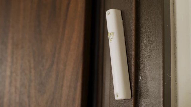 Close Up of hand touching a Jewish Mezuzah on a door