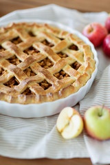 food, culinary and pastry concept - close up of apple pie in baking mold on kitchen towel