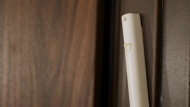 Extreme close up of a hand touching a Mezuzah upon entering a house