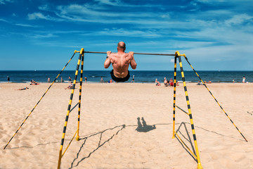 sports man doing exercises on the beach bar
