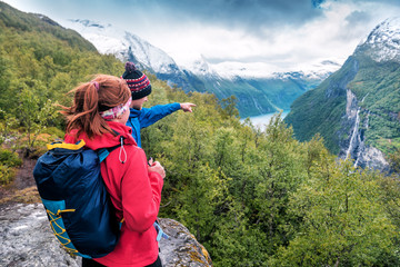 tourist guide shows a girl waterfall in the mountains of Norway