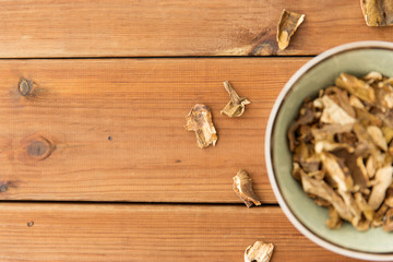 culinary, food and cooking concept - dried mushrooms in bowl on wooden background