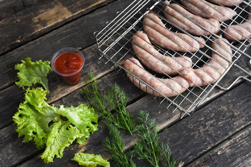 Raw barbecue sausages on a grill grate on a kitchen table background.