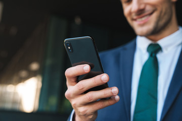 Croppes image of smiling positive young business man using mobile phone.