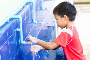 Health care and kid concept. Asian child boy washing his hands before eating food and after play the toys at the washing bowl. A boy aged of 5 years old.