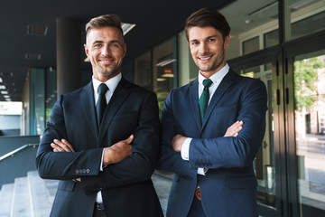 Portrait closeup of two successful businessmen partners smiling while standing outside job center...