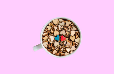 small blue and red wooden heart in white cup isolated on pink background, love concept, top view