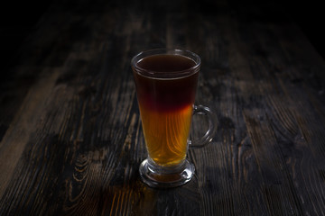 A cup of layered tea on a dark wooden table. Concept for menu.