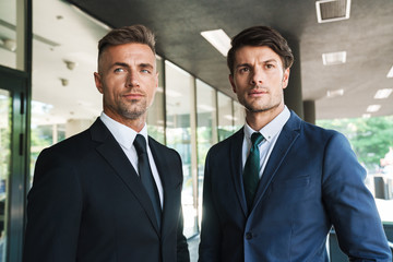 Portrait closeup of two beautiful businessmen partners standing outside job center during working...