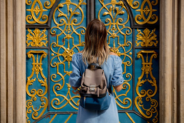 back view of a girl with a backpack standing near a beautiful door