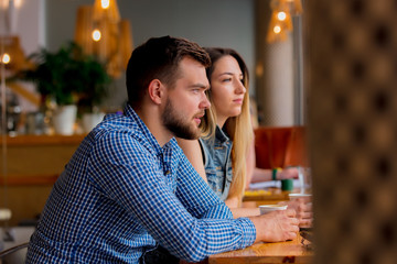 young couple sitting at a table in a cafe and drinking coffee