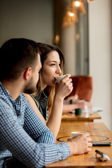 young couple sitting at a table in a cafe and drinking coffee