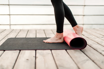 Woman rolls yoga mat before asana training at the sea on sunrise
