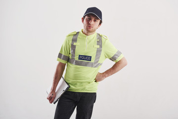I'm listening to you. Policeman in green uniform stands against white background in the studio