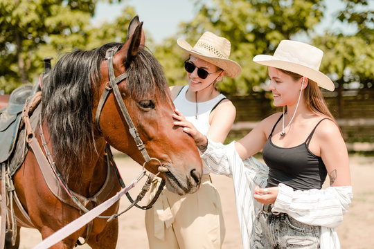 Cowgirls with a horse on a western farm touching a horse
