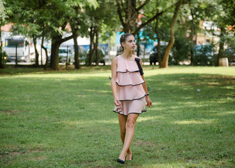 Young woman in beautiful dress walking in summer park at sunny day