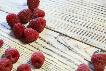 Fruit background. Ripe red raspberry berries on a light wooden surface. Horizontal, close-up, free space on the right. Healthy eating concept.