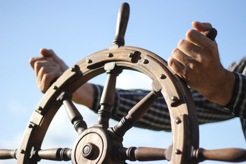 Steering hand wheel ship on sky background, hand hold