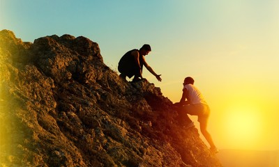 Man Rock Climbing with another Man Helping