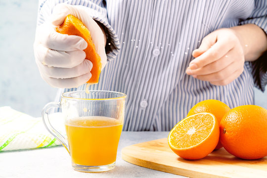 woman squeezes orange juice in a glass cup