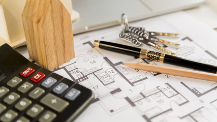 Black fountain pen; pencil; keys; wooden house block and calculator on blueprint