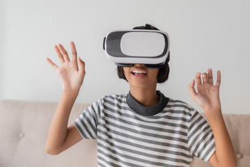 Beautiful Asian girl are looking through vr glasses to play games at home, woman is using glasses with virtual reality headsets at the desk