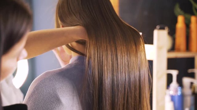 Long dark hair of a young girl. Brilliant and silky hair after keratin straightening. The effect of keratin, botox, straight hair. The concept of beauty salons, beauty.