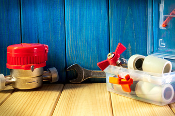 New water meter with fittings and wrench on a wooden background.