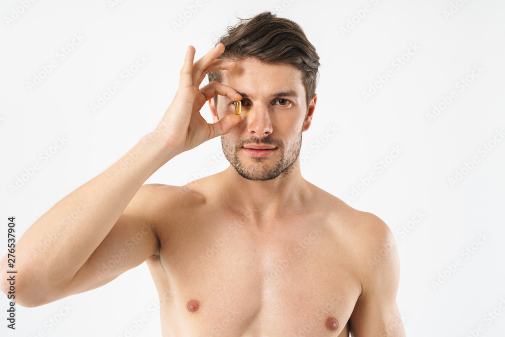 Poster Photo closeup of attractive naked man looking at camera and holding vitamin pill