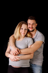 a man and a pregnant woman couple in their ninth month of pregnancy are embracing against an...